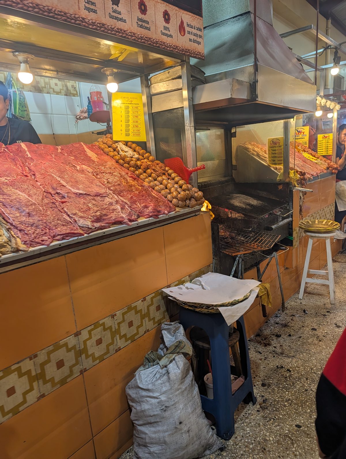 Butcher stall with tasajo and chorizo next to its charcoal grill in Pasillo de Humo