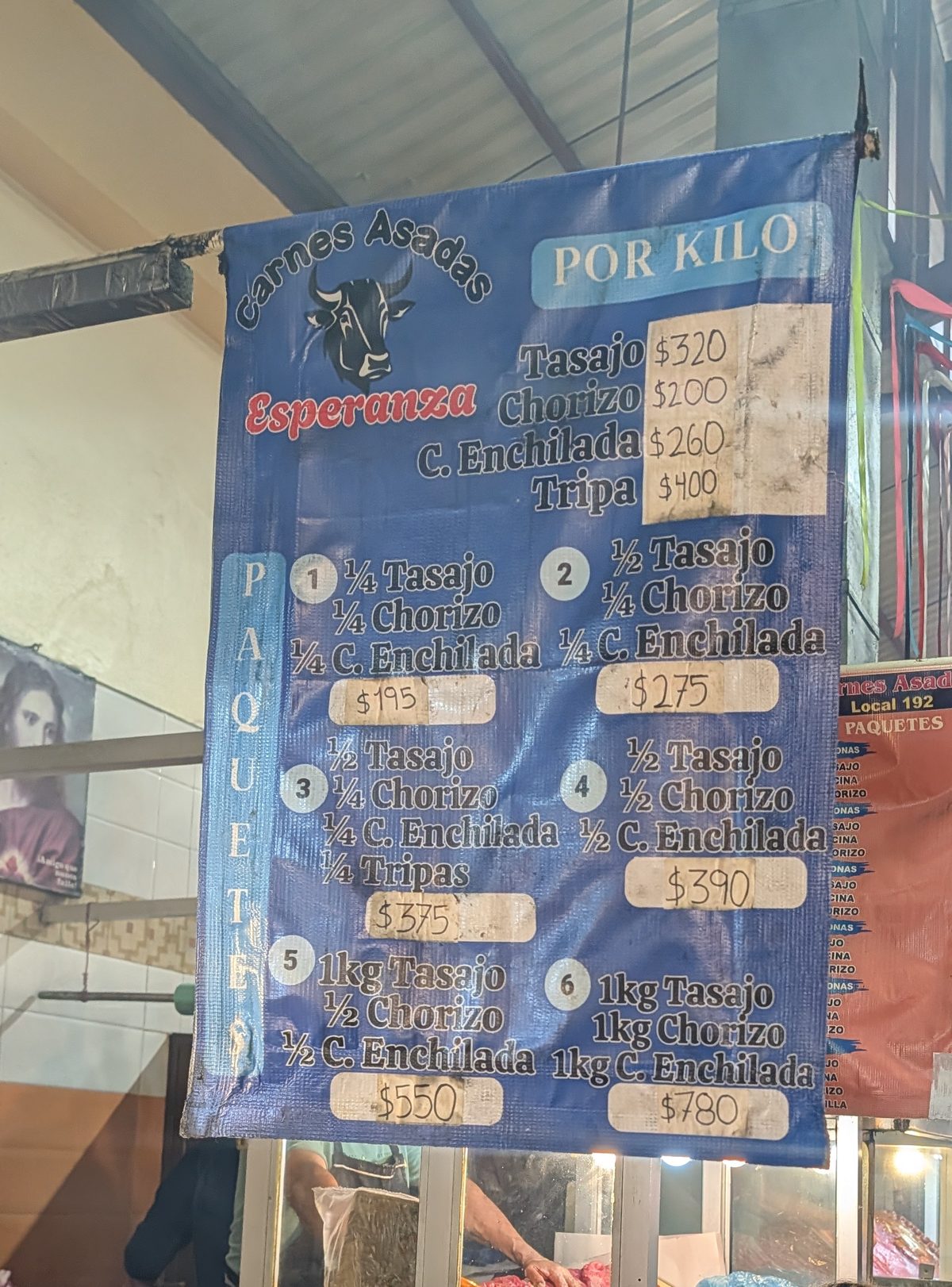 Carnes Asadas price board at Pasillo de Humo listing tasajo, chorizo, cecina enchilada and tripa prices per kilo and meat packages