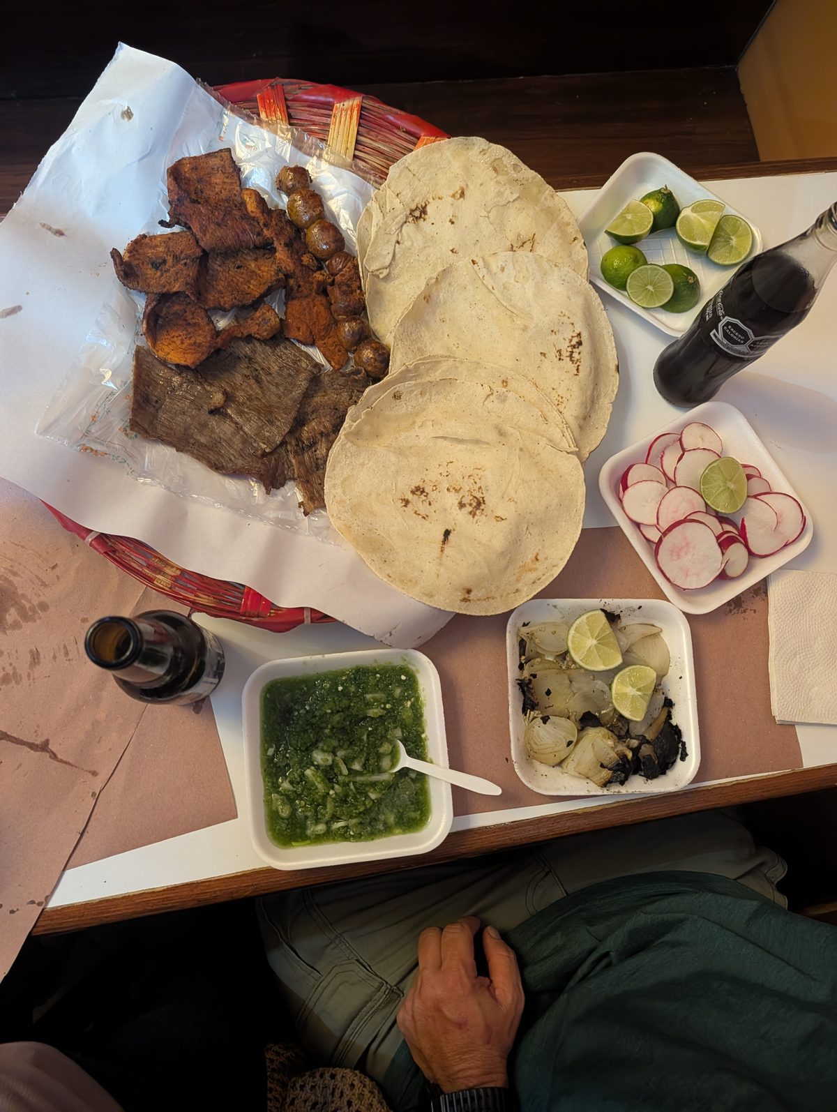 Overhead view of tasajo, cecina, chorizo, tortillas, salsa, limes and radishes at Pasillo de Humo
